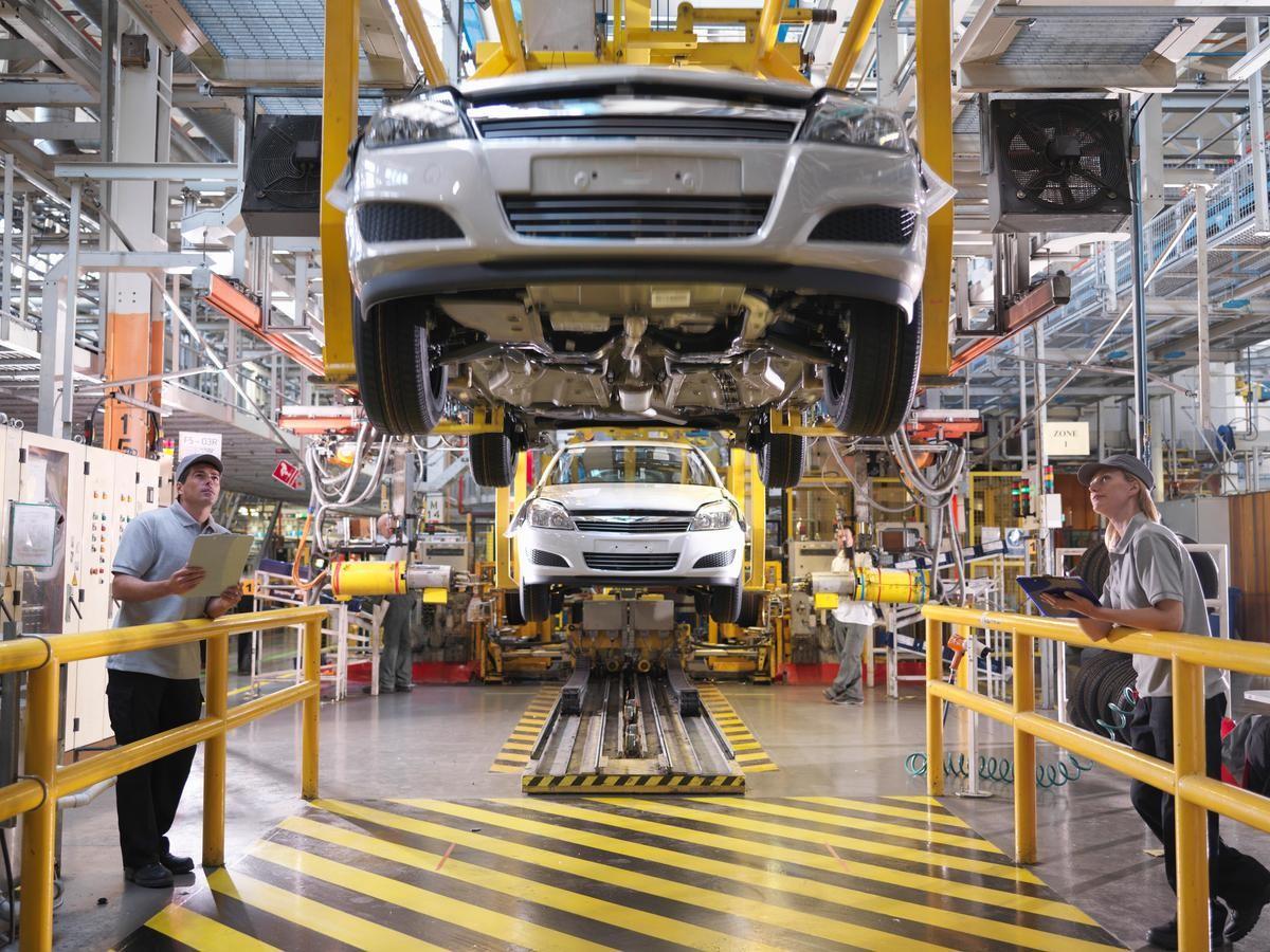 People watching as cars go by on a production line.