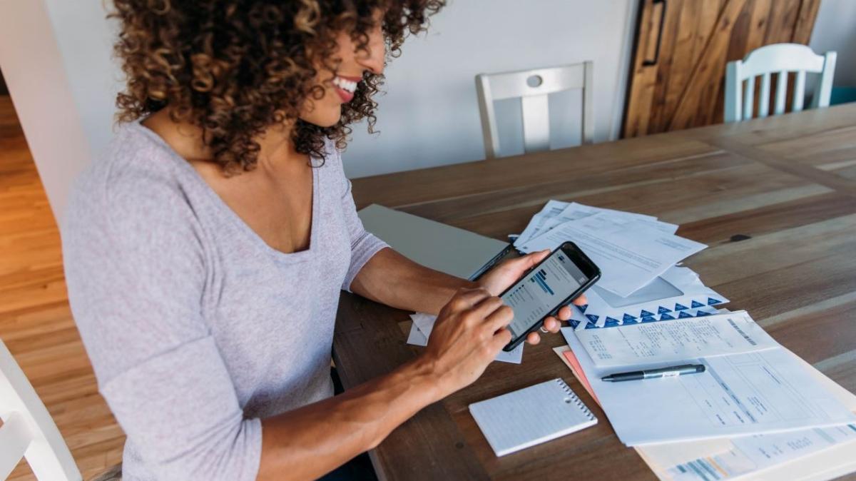 Person using their phone at a table spread with papers