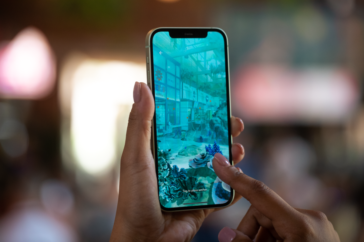 Two hands holding and interacting with a phone open to an 'underwater' scene.