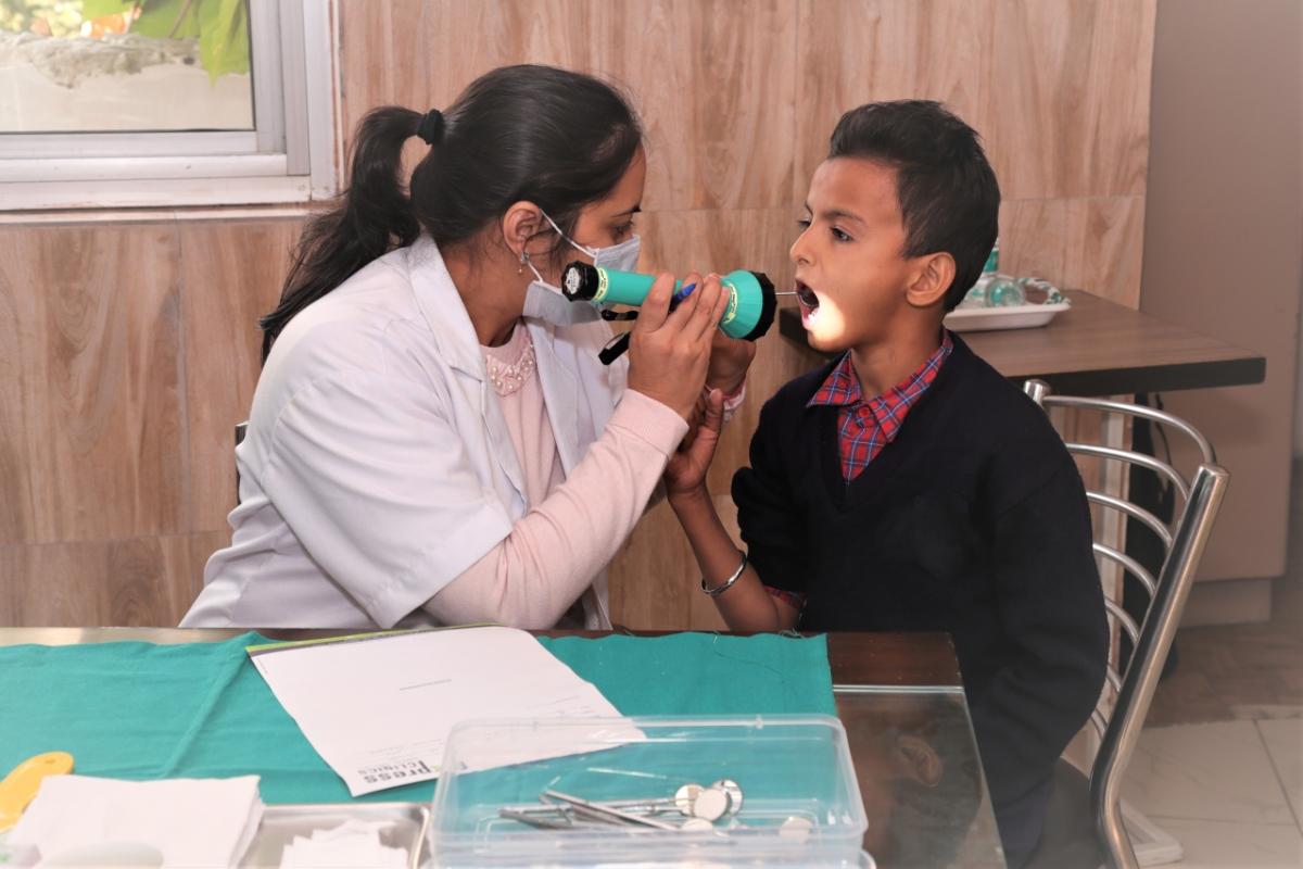 Person looking in a childs' mouth with a flashlight