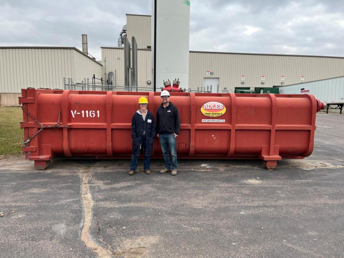 Two people in front of a tank