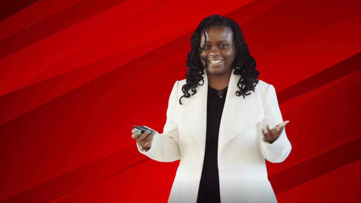 A person smiling with their hands out in front of a red background