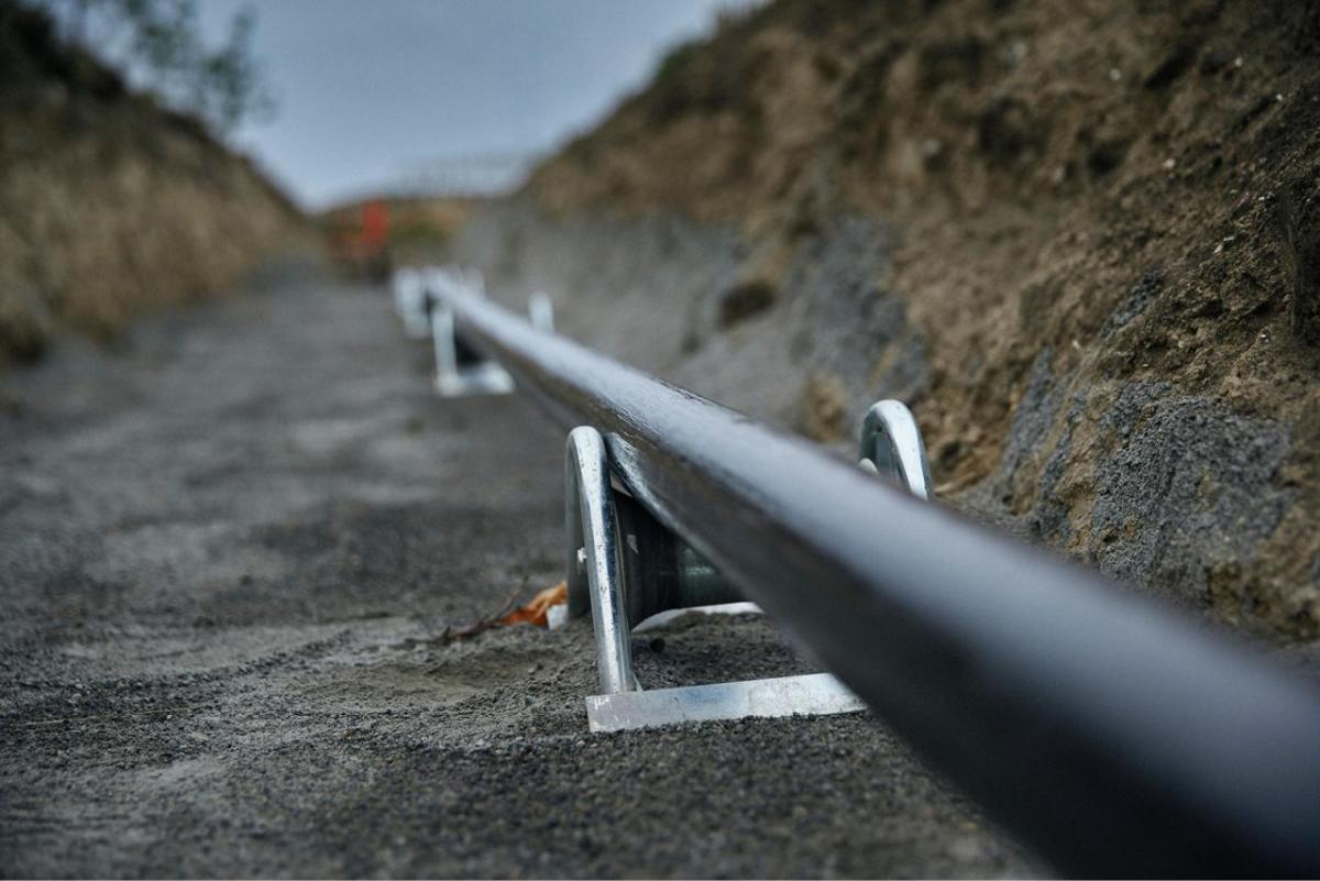 A long cable in a trench in the ground.