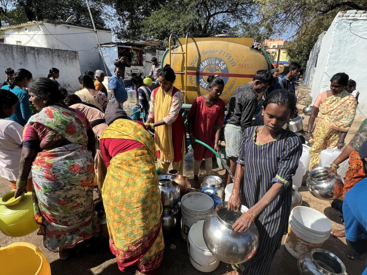 People gathered, collecting water in jugs.