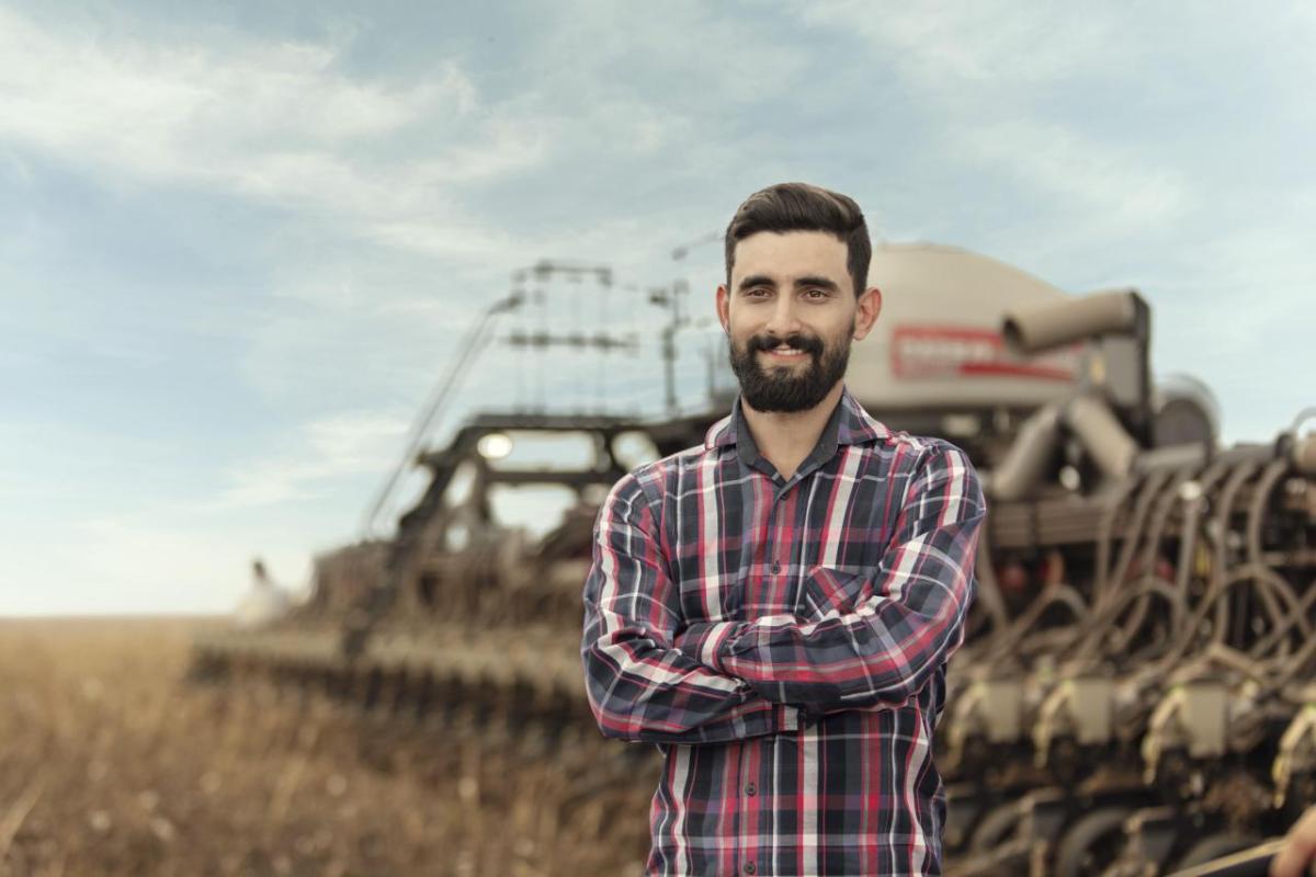 A person standing in front of a tractor in a field