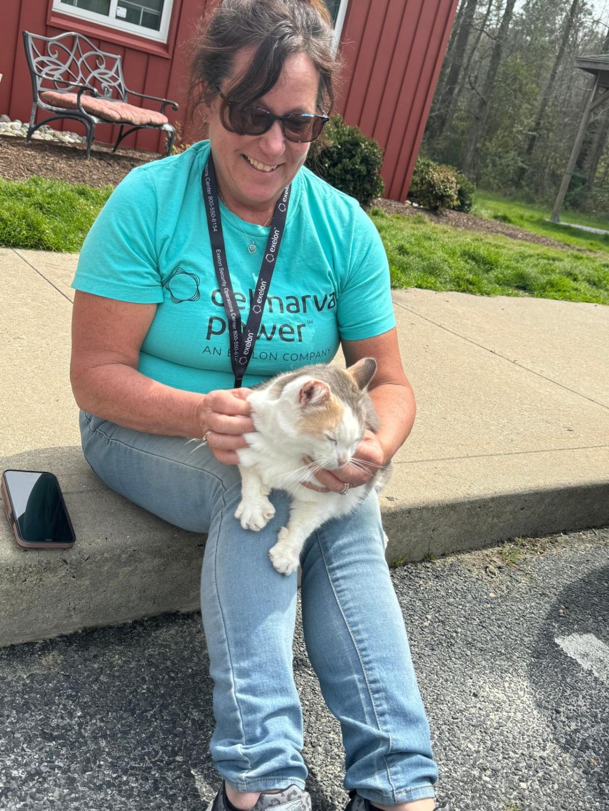 Volunteer sitting with a cat on their lap.