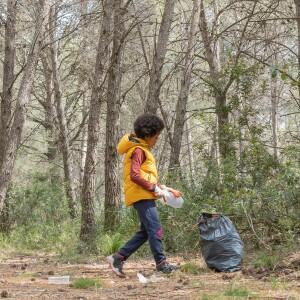 Child picking up a plastic bottle