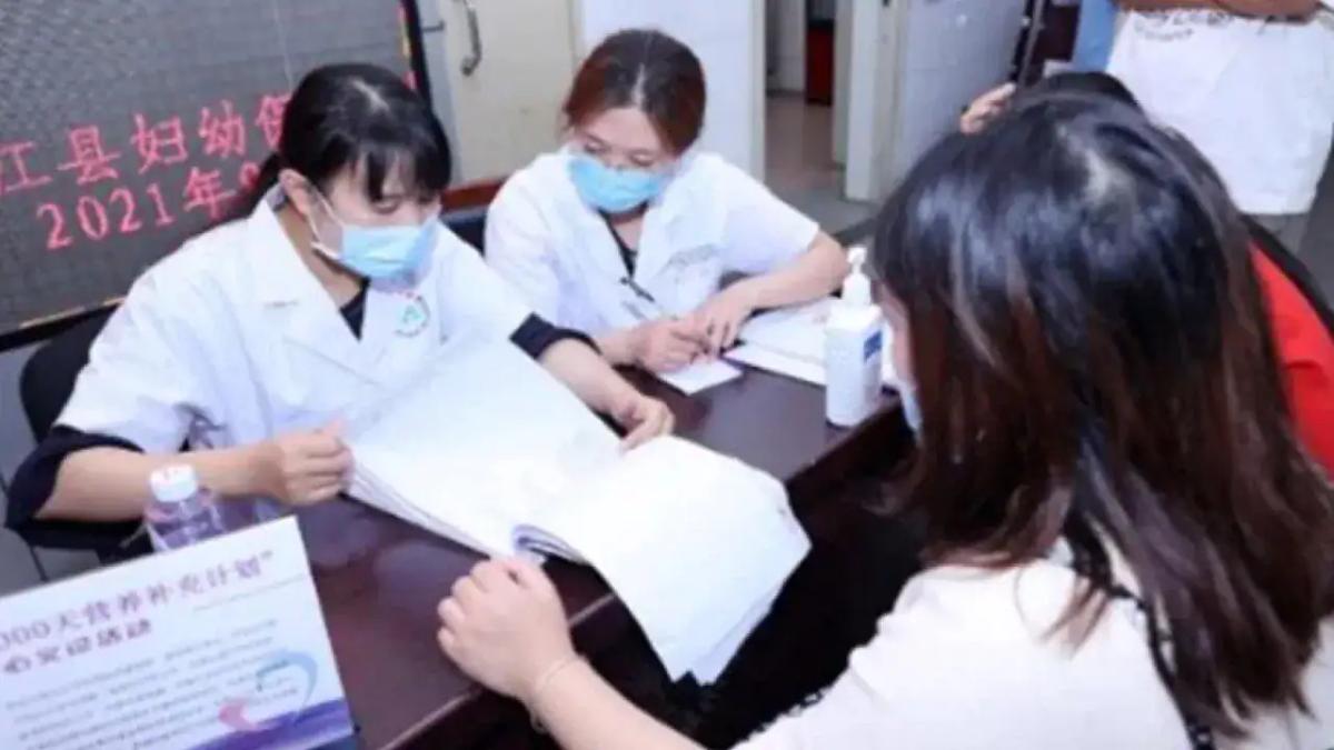 two medical professionals flipping through a stack of papers, others seated on the other side of the table