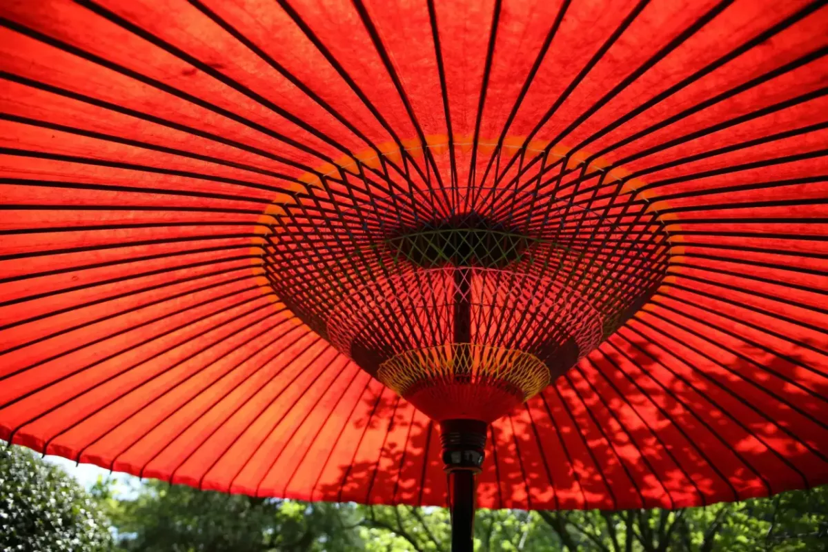 An open, red, fabric umbrella outside.