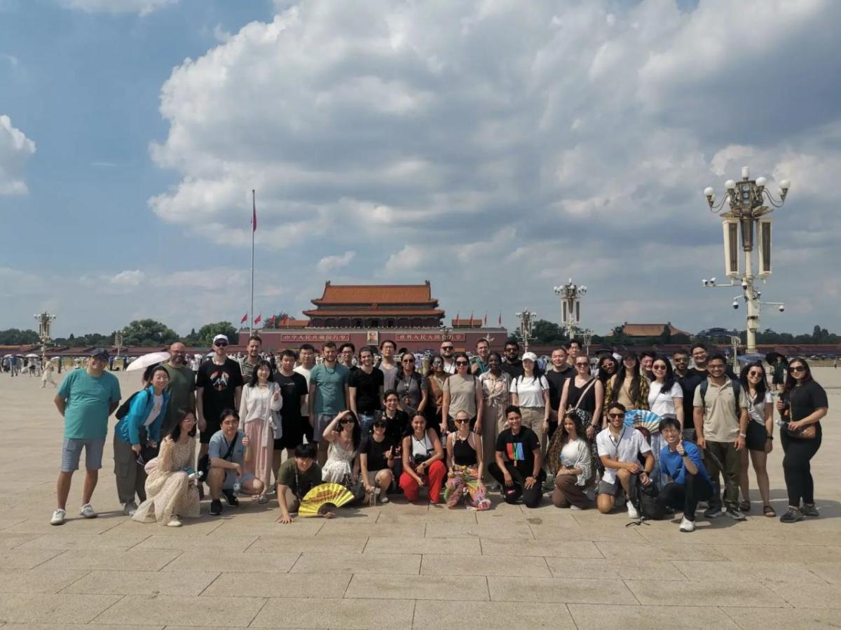 A large group posed outside, a palace in the background.