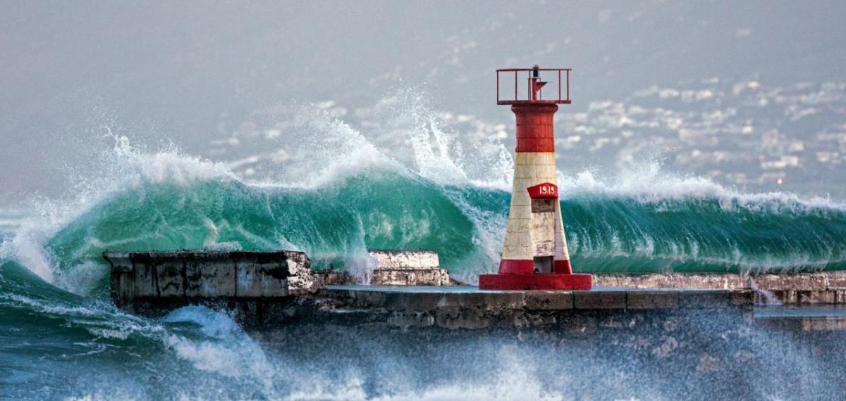 Tall waves crashing over a wall with beacon.