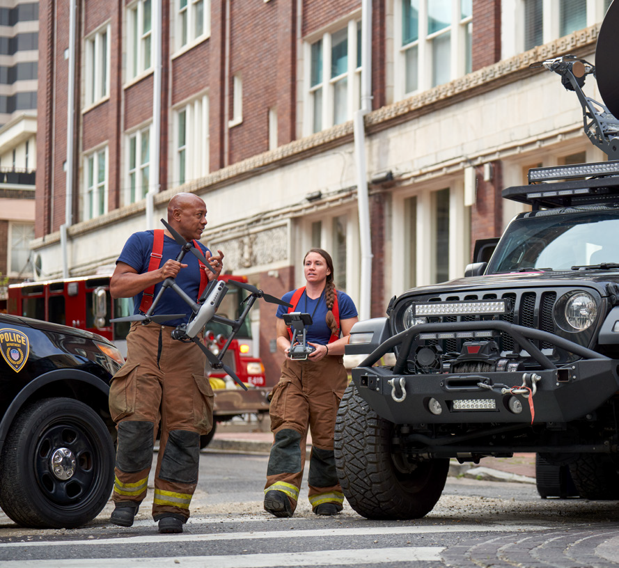 Firefighters carrying a drone near vehicles