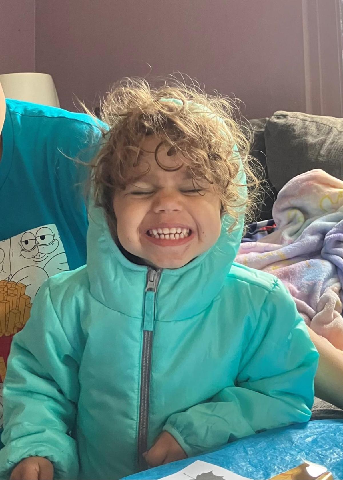 A smiling child in a teal coat