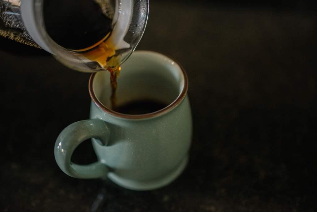 Coffee is poured into a mug from a carafe.