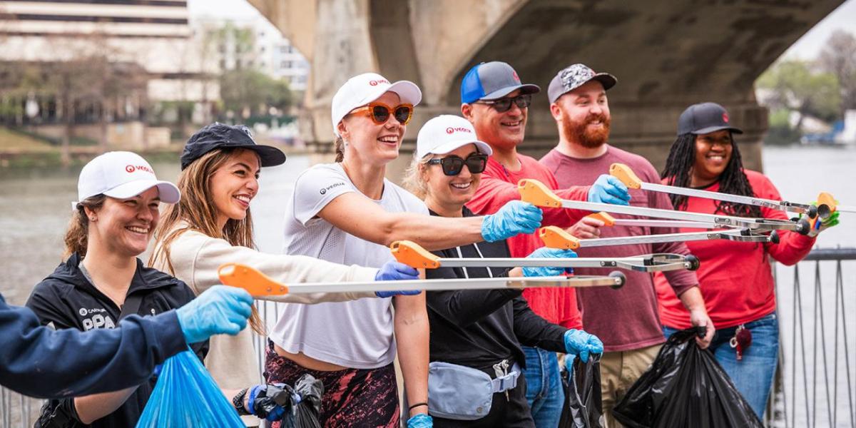 Smiling volunteers posed together extending litter pickers.