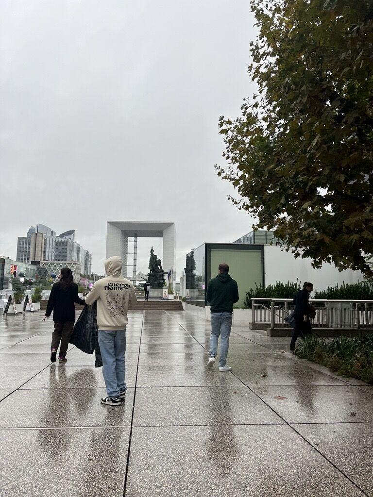 People walking outside on a rainy day, some collecting trash.