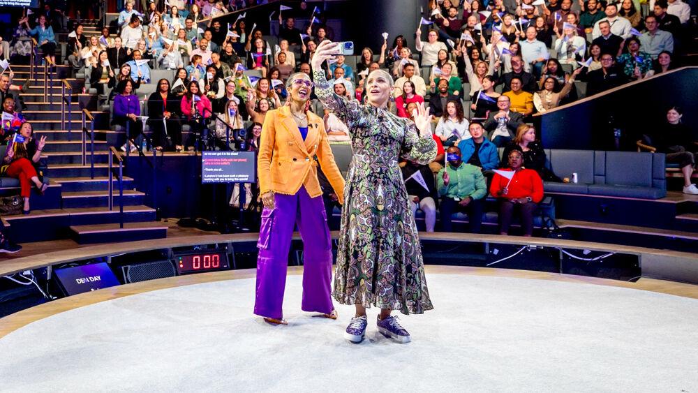 Two people taking a selfie at an event with the audience 