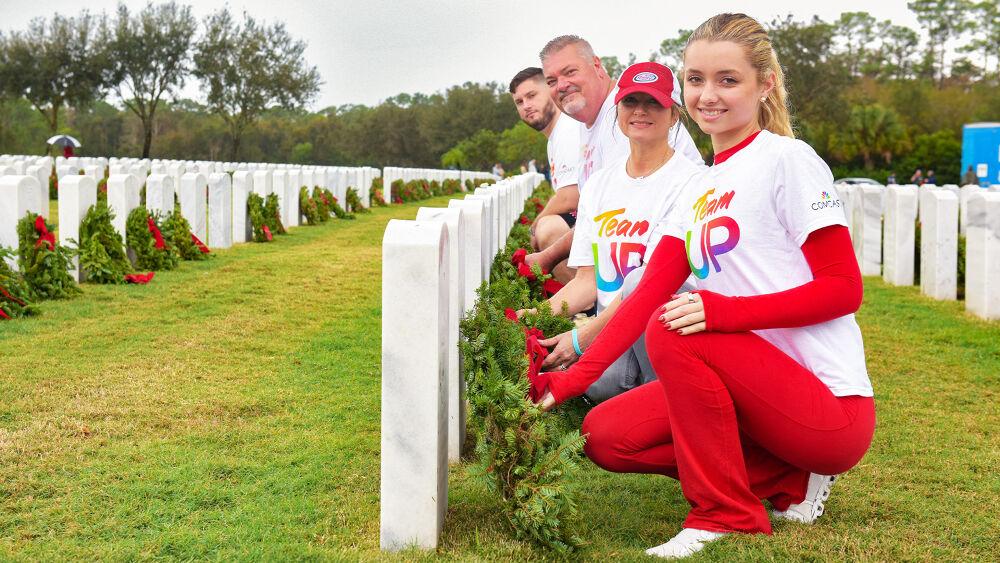 group posing with wreaths at headstones