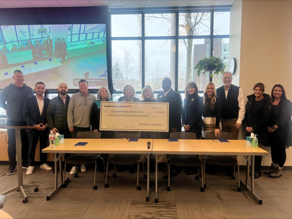 People standing behind a desk, holding an oversized check