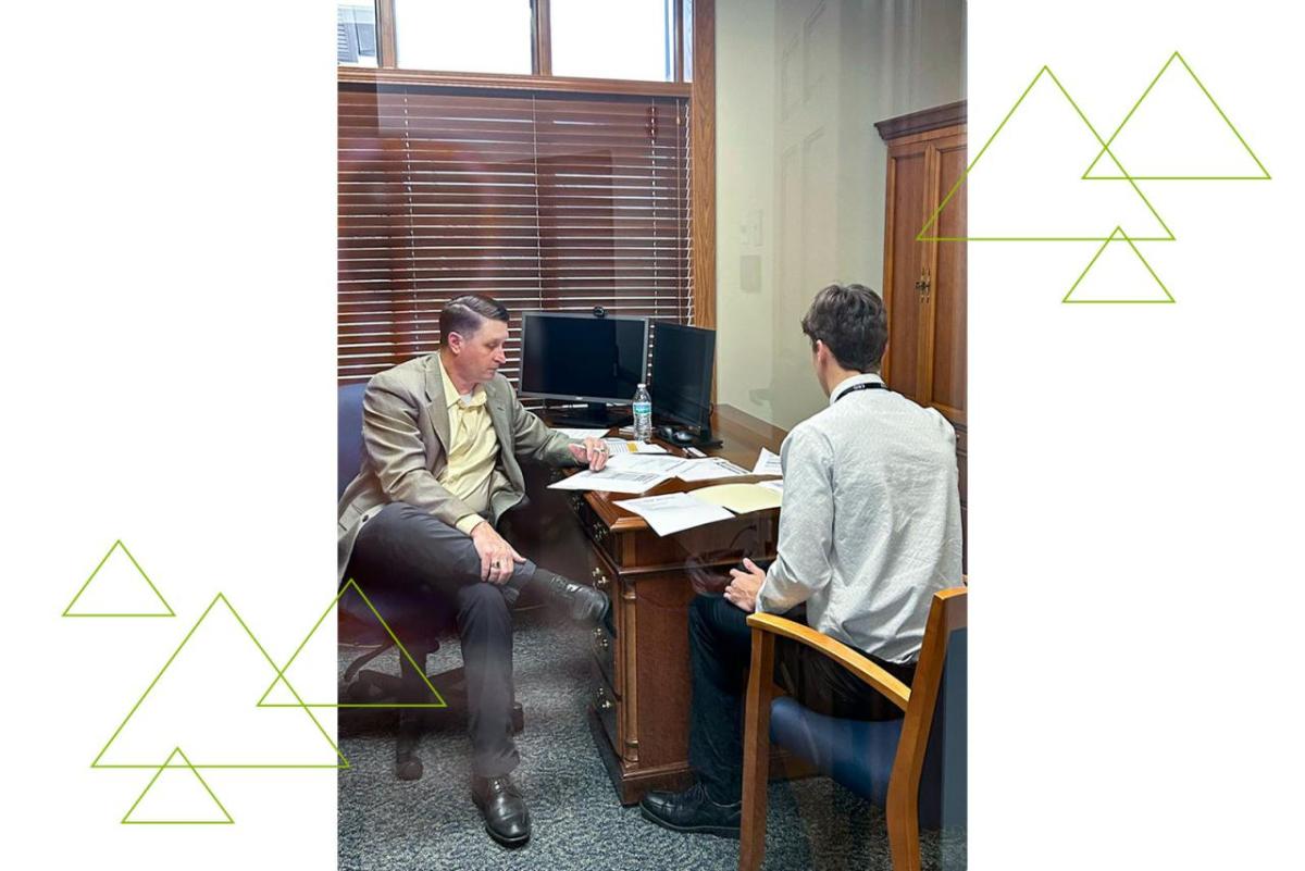Two seated people looking at papers on a desk