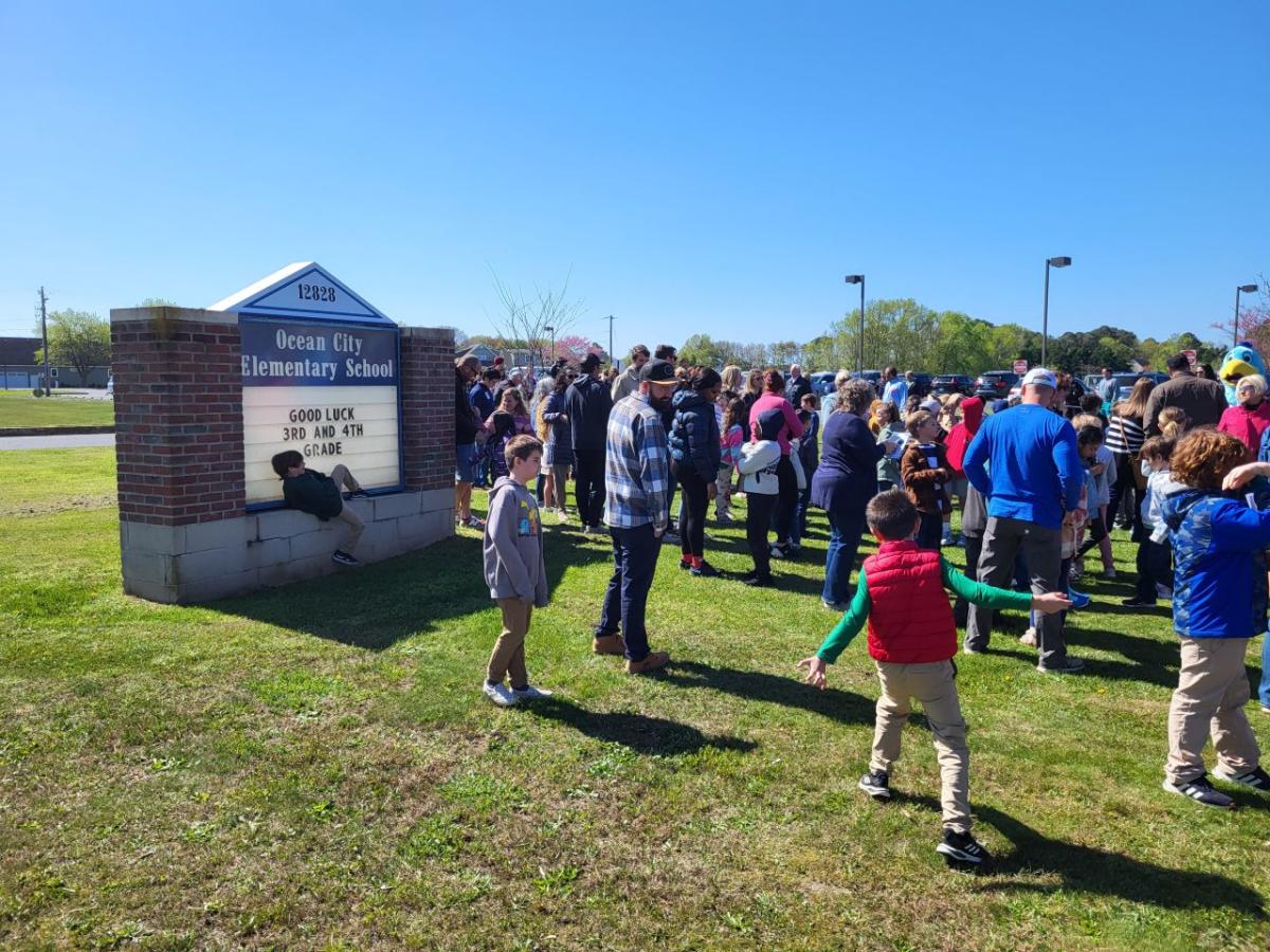 A large group standing by a sign for the school.