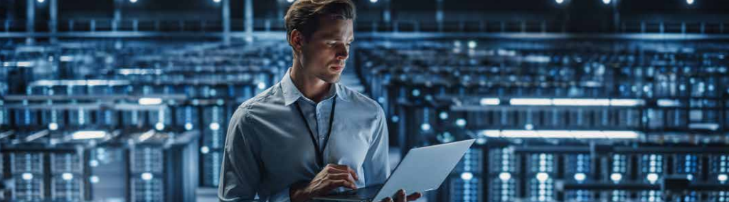 A man holding a laptop in a server room