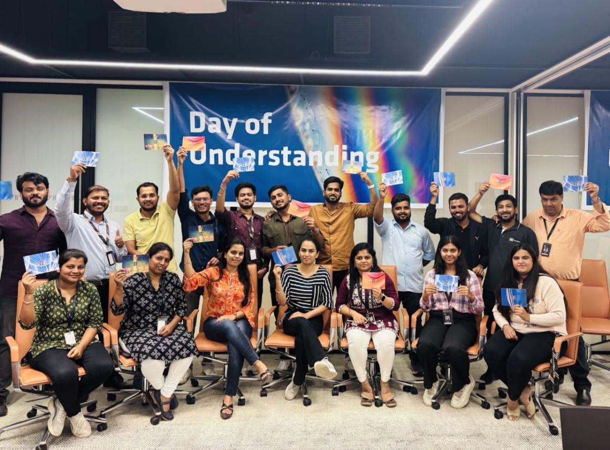 A group posed, each holding up a card. "Day of Understanding" poster behind them.