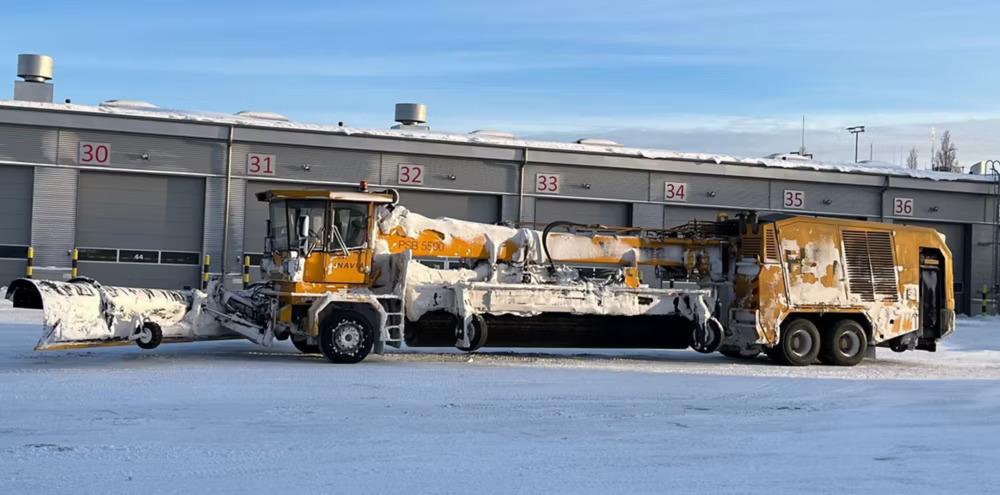 A large de-icing machine outside covered in snow