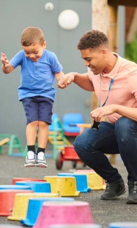 An adult holding a child's hand as they jump along colored spots.