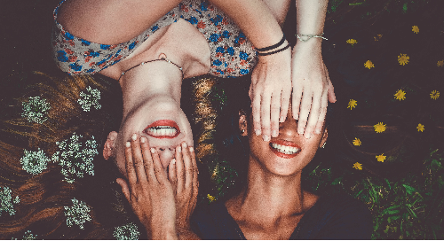 Two women both covering their eyes.