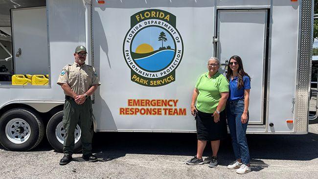 3 people standing in front of emergency response trailer