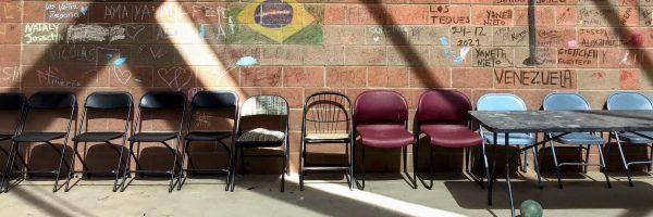 a row of empty chairs against a brick wall 