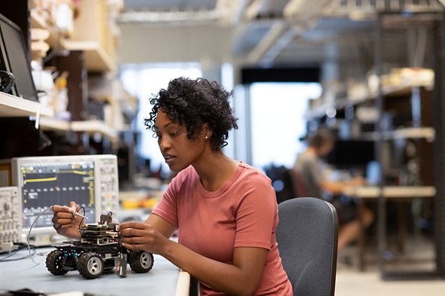 A person working on a small robotic vehicle