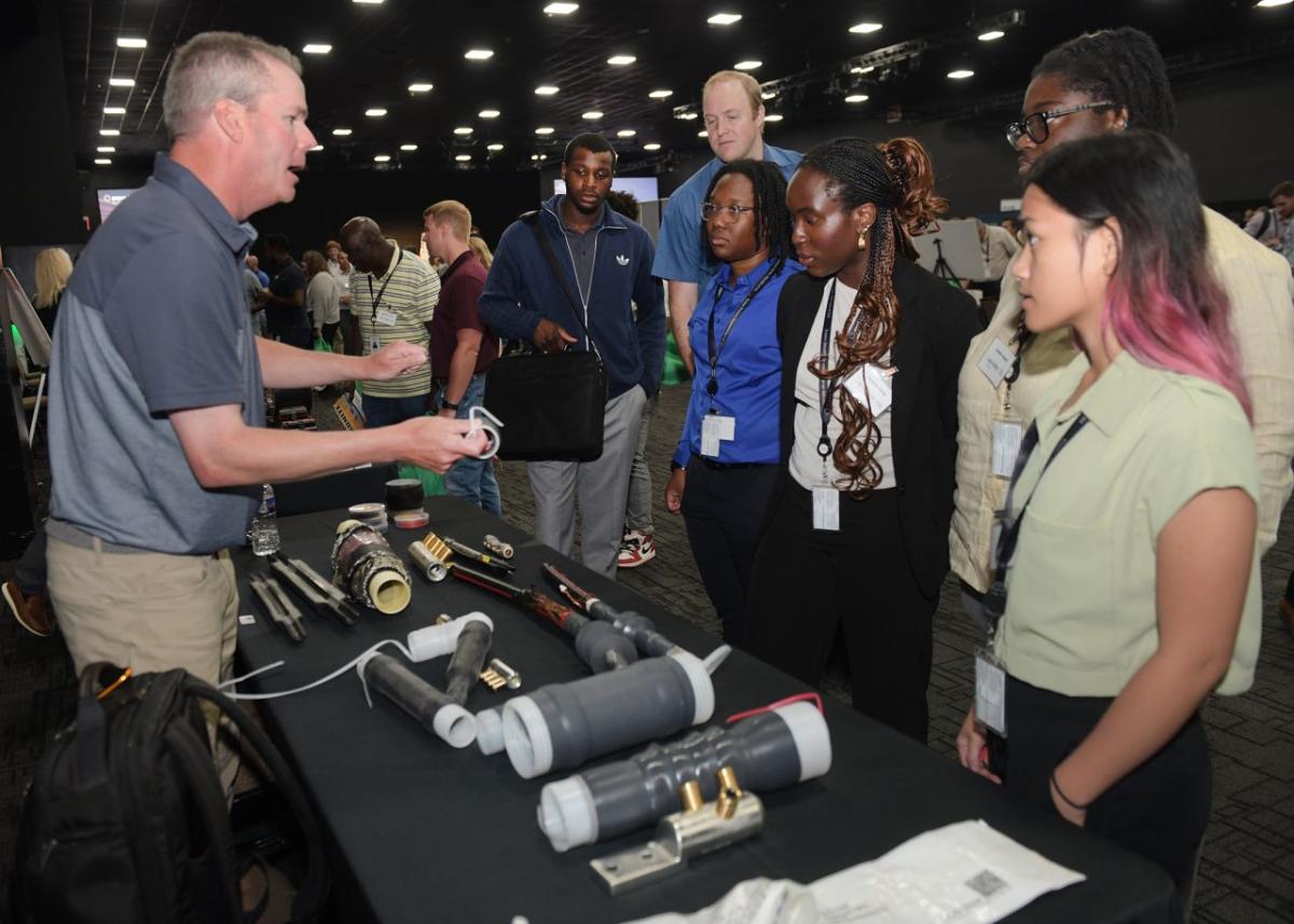 A person standing at a booth showing others parts.