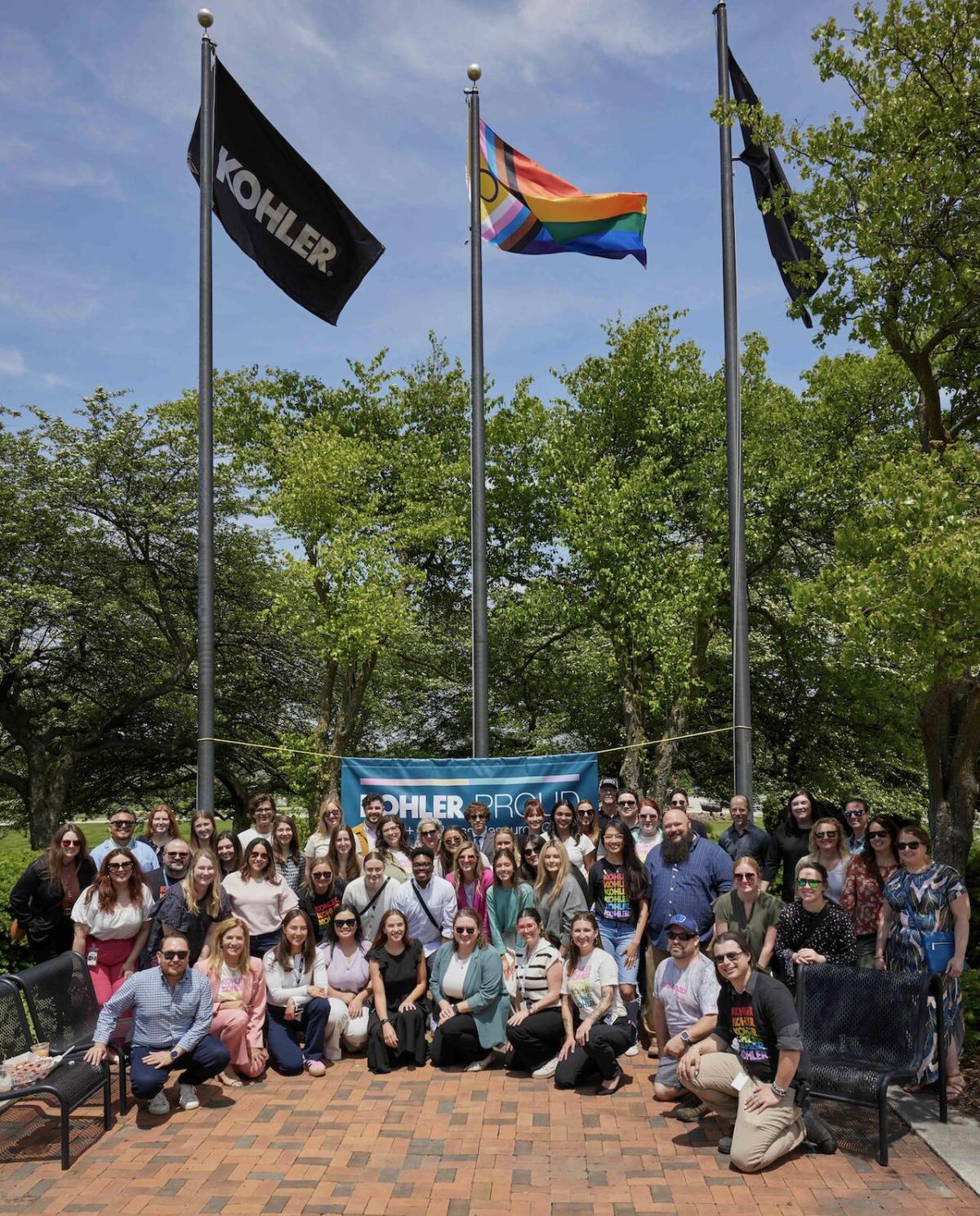 A group posed in front of flags on poles.