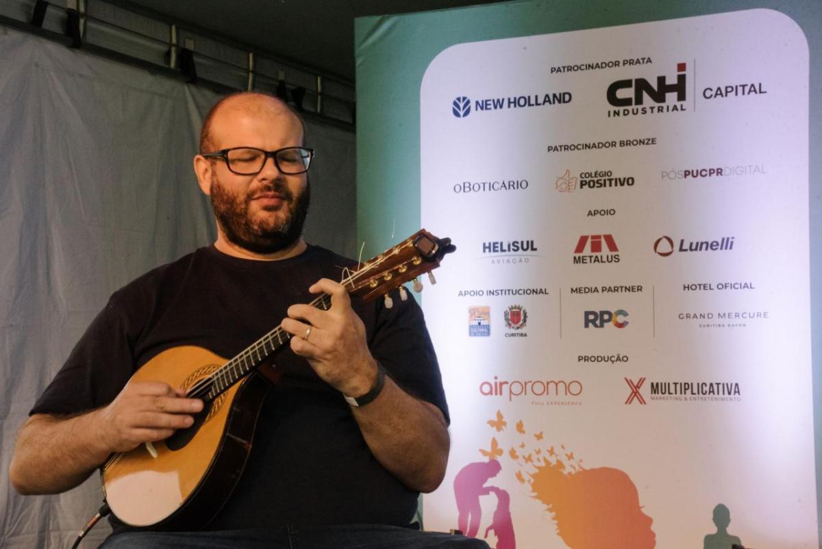 man in a black t-shirt and glasses playing a mandolin