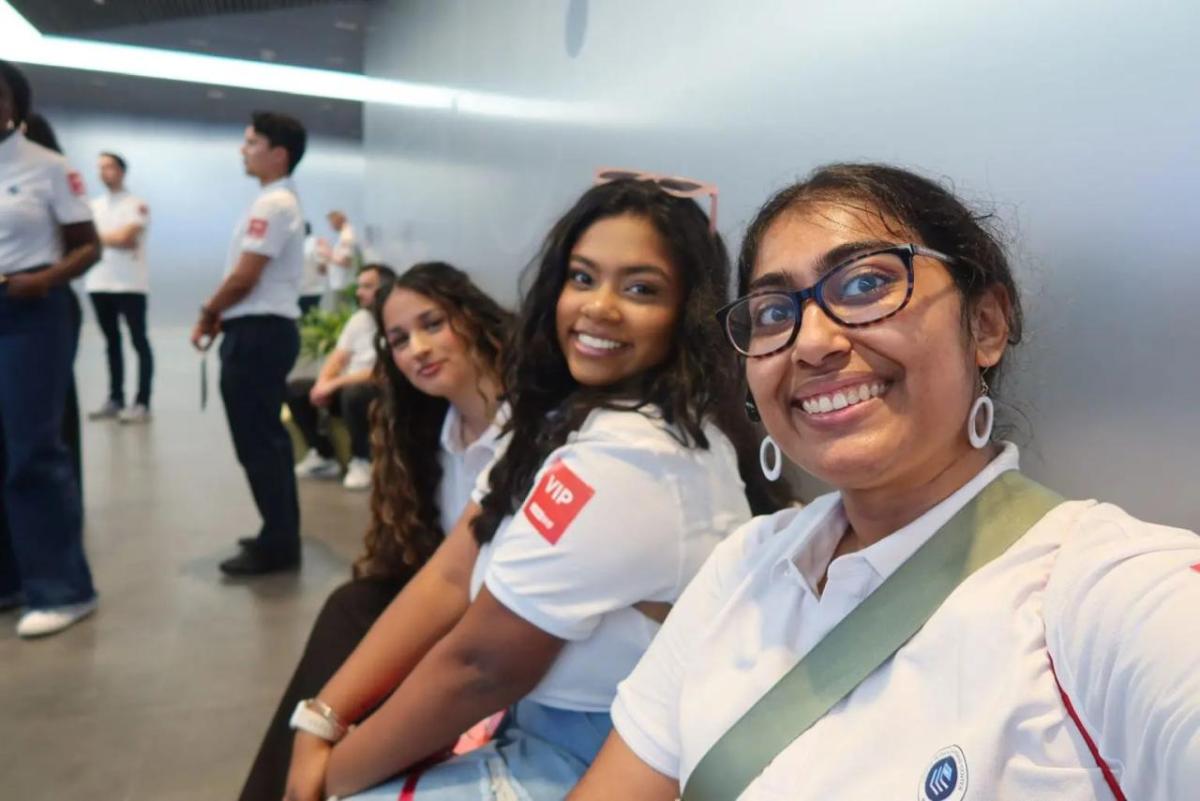 Three people in matching white shirts taking a selfie.