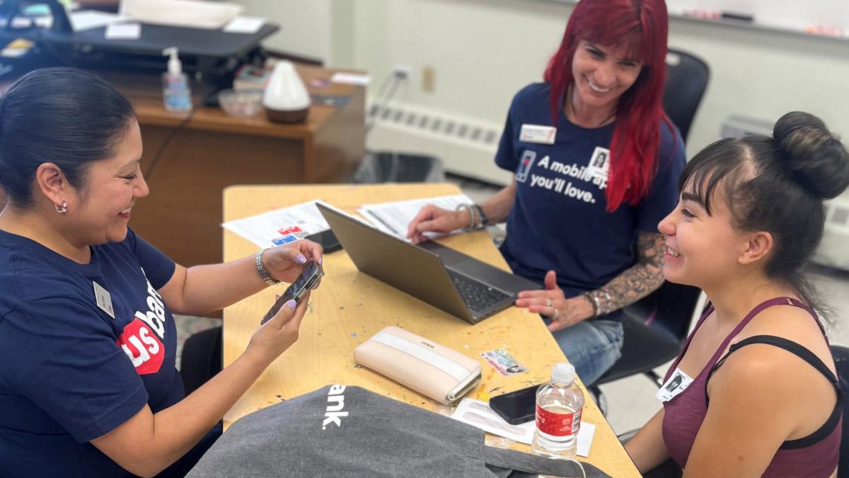Gina Chavez, left, and Krystina Pombo teach financial literacy to a Florence Crittenton graduate at Senior Bank Account Day in June 2024. " "