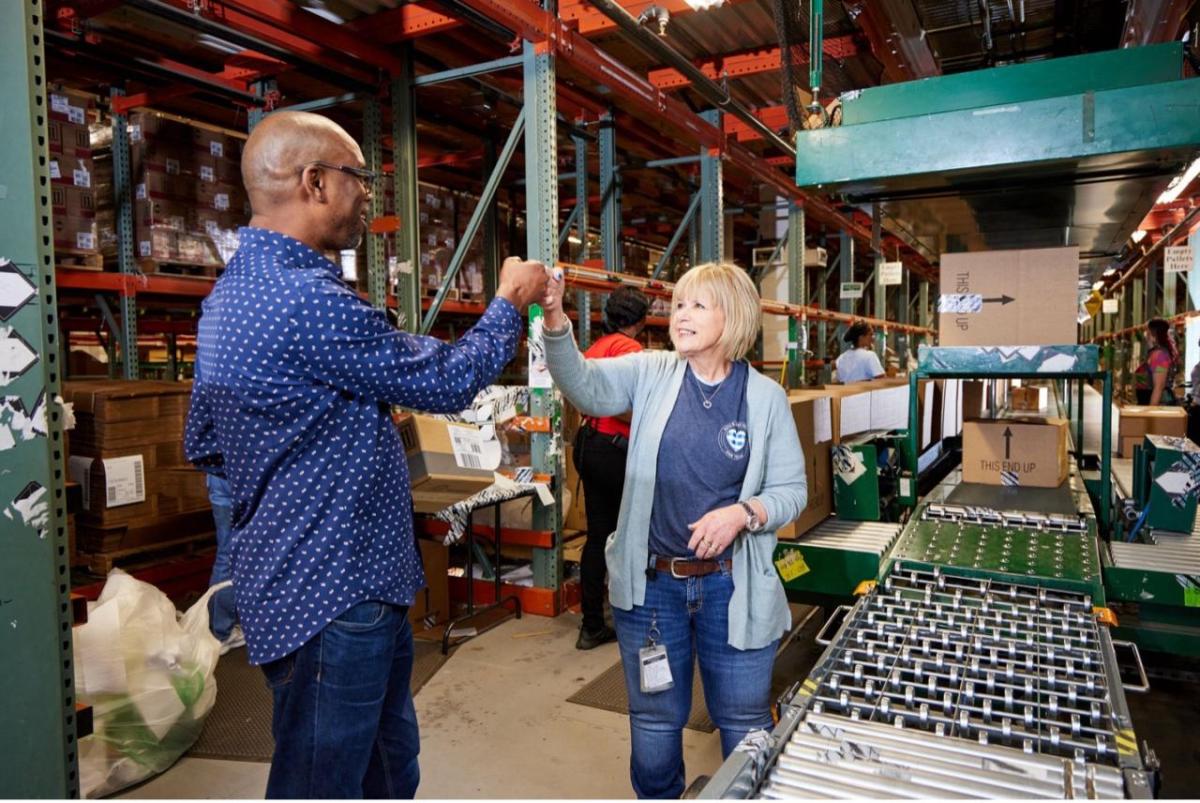 Two employees fist bump in a fulfillment center