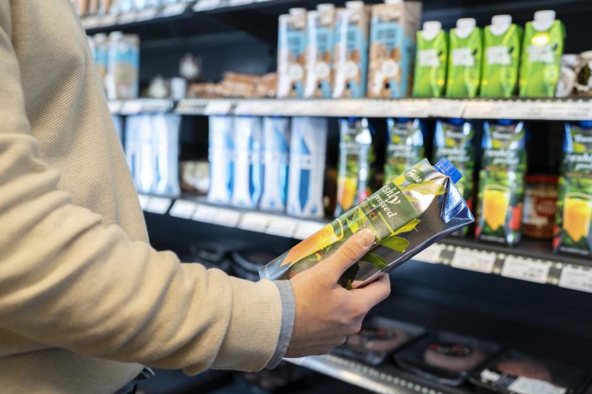 A person holding a beverage container in a store.