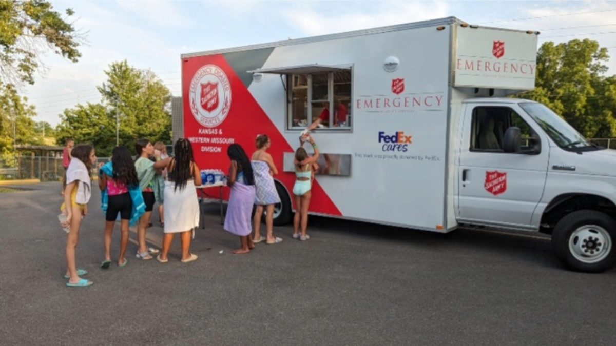 A line of people in front of a truck with side window opening.