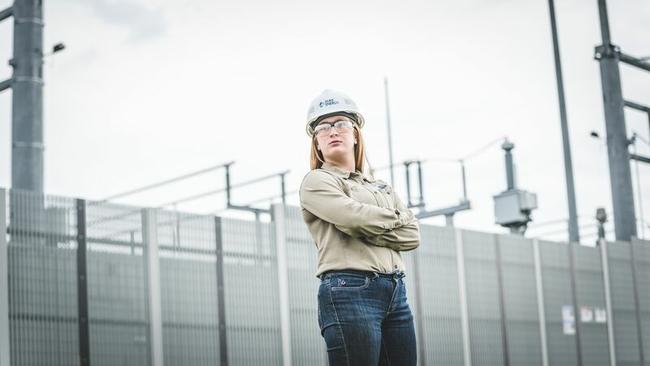 A worker in a hard hat, standing with crossed arms