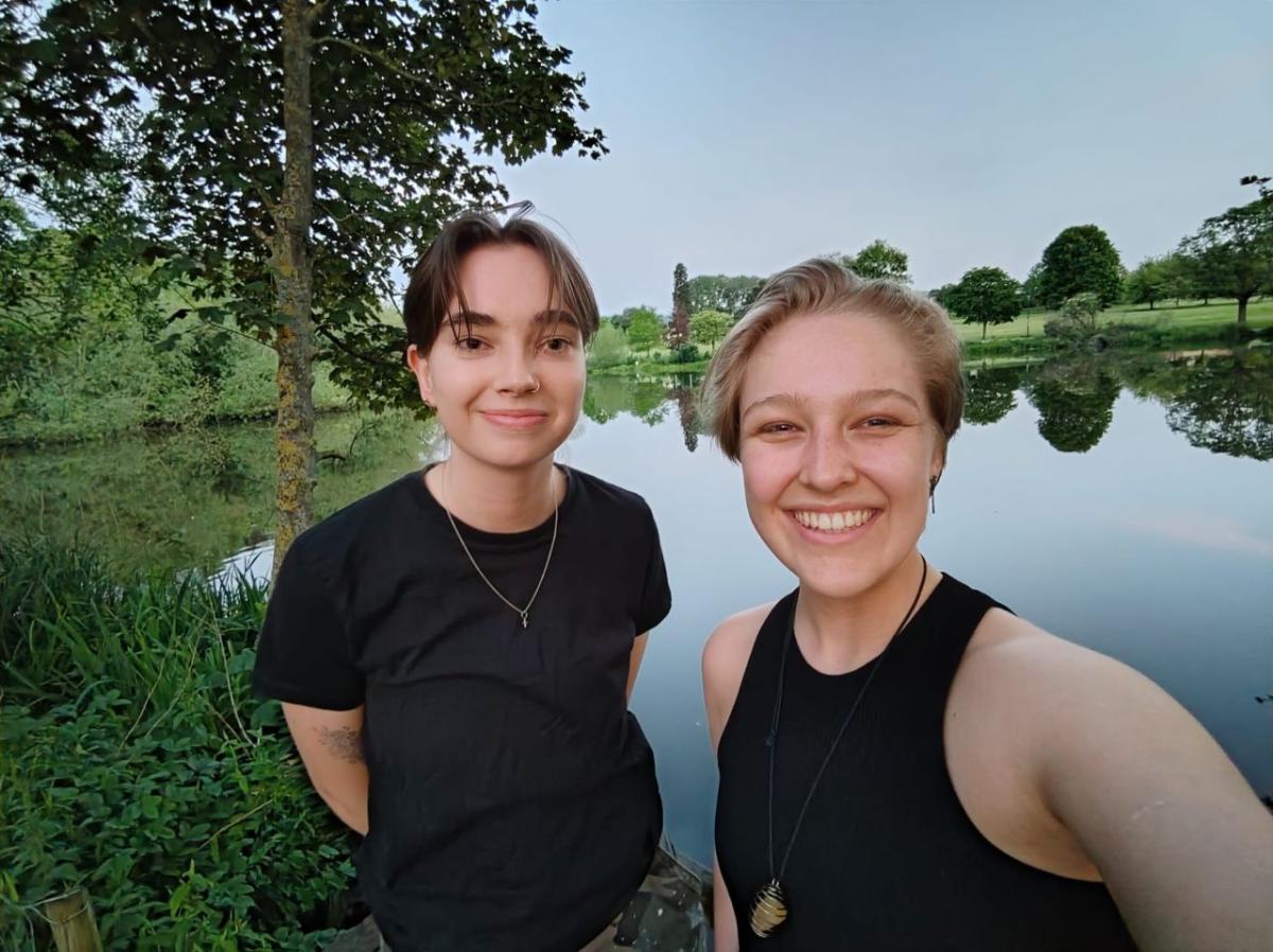 Two smiling people in a park setting.