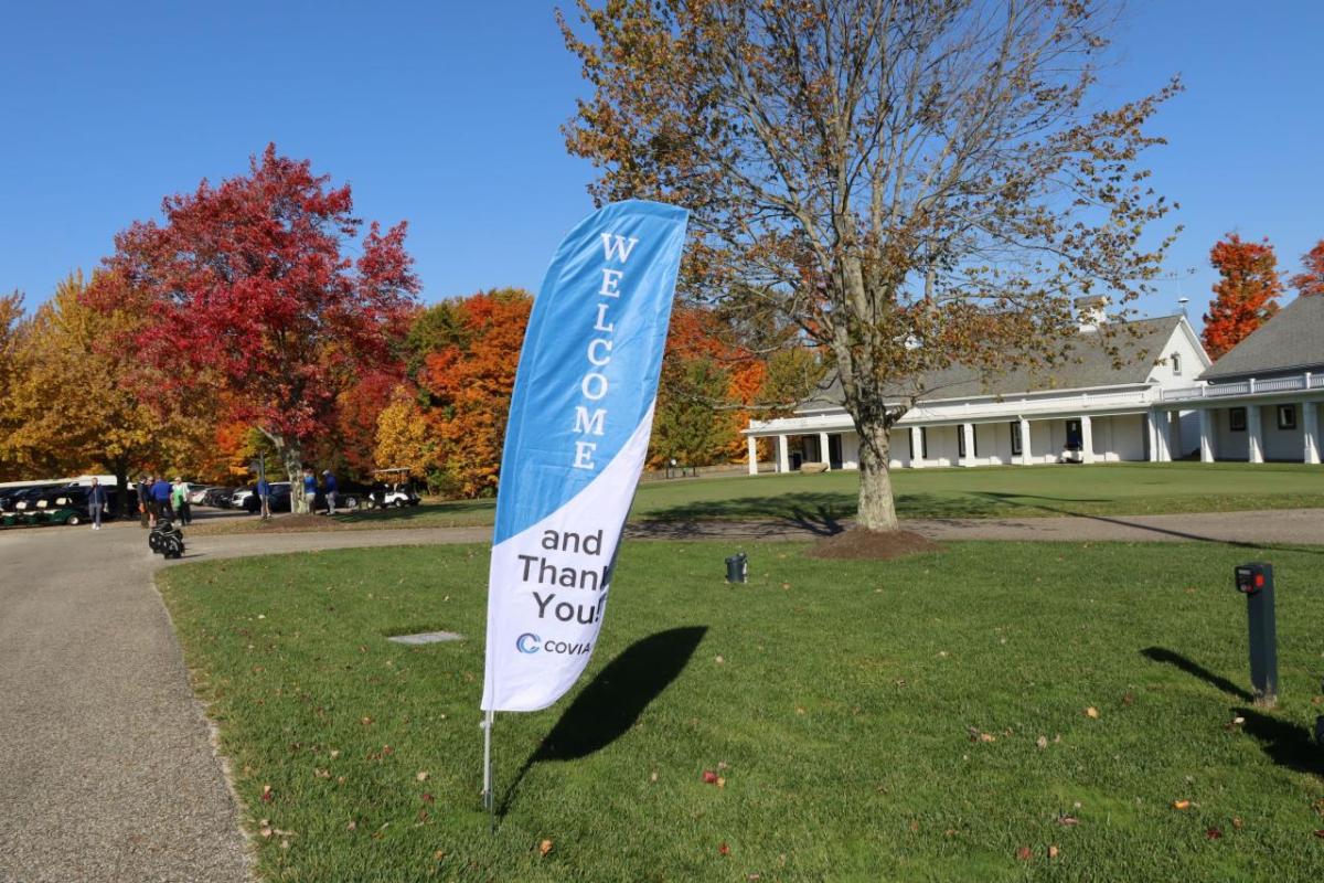 A Welcome flag on a lawn outside a golf course.