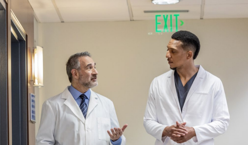 Two medical professionals talking and walking down a hallway.