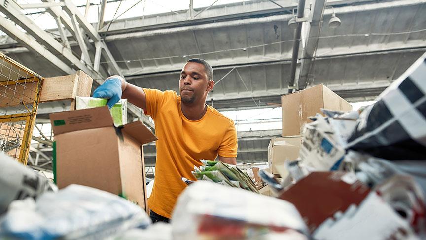 A person sorting through boxes and piles of things in a warehouse