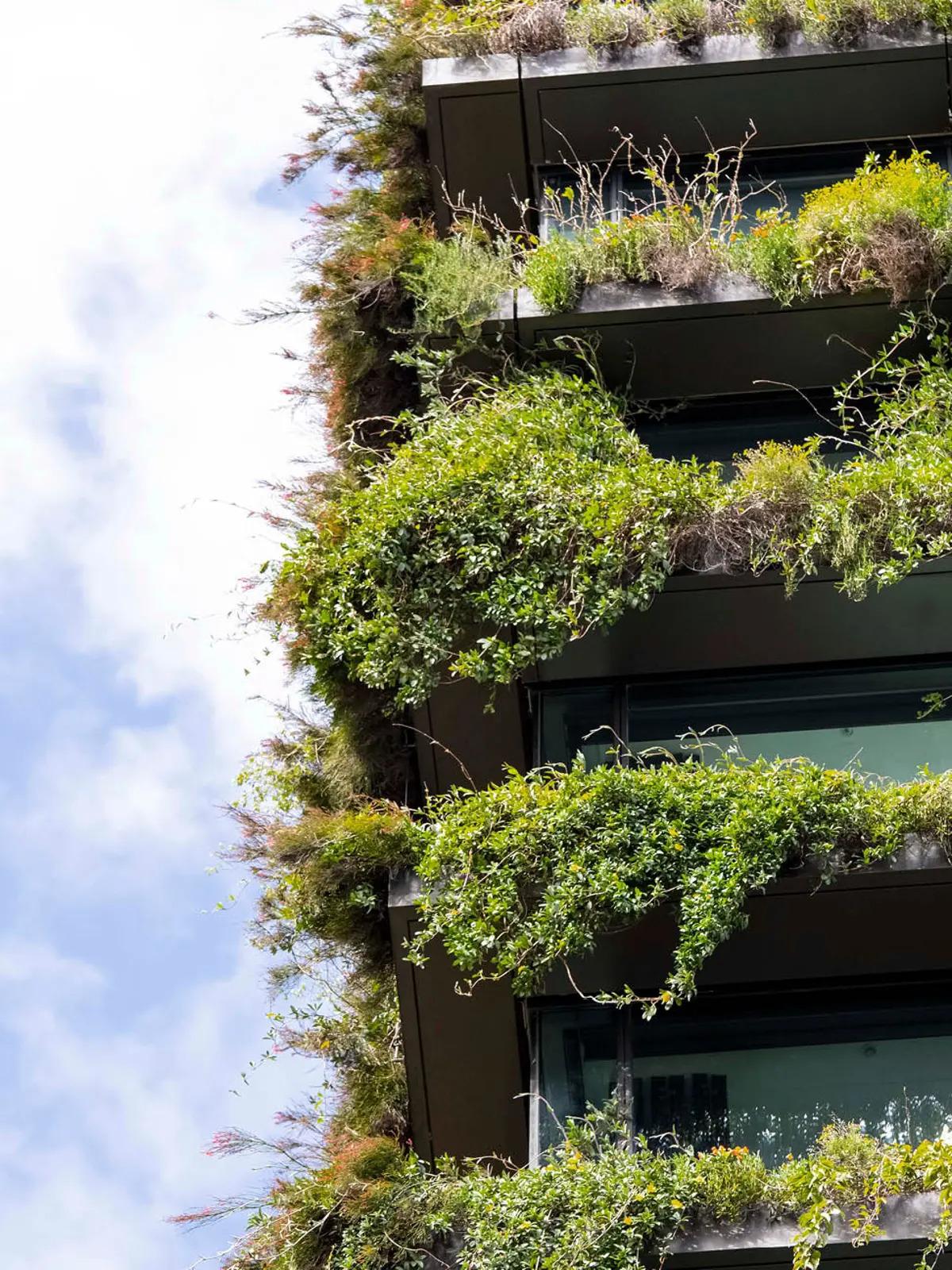 A multi-story building with overflowing plants on every balcony.