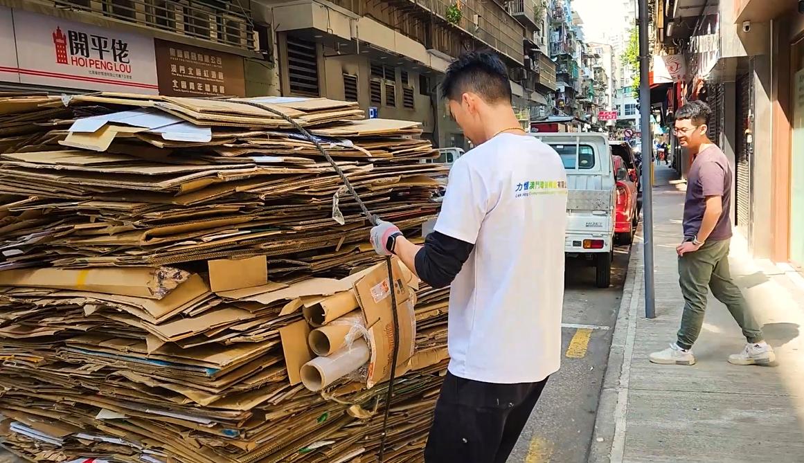 A person tying up a large bale of cardboard.