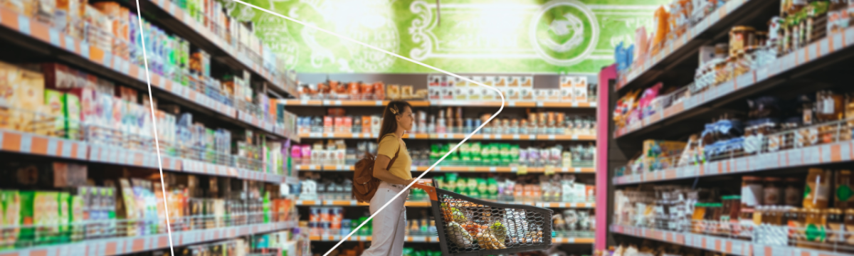 a person pushing a grocery cart in a store, aisles filled with food