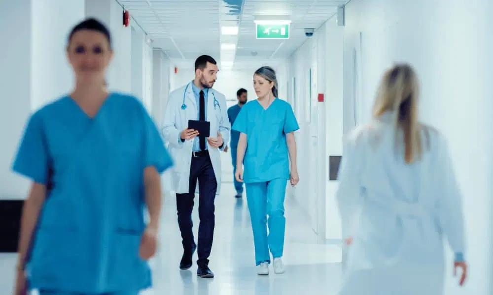 Medical professionals walking down a hallway. Two talking together.